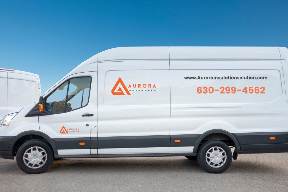 A side view of a white delivery van featuring the logo and contact information for Aurora Industrial Solutions.