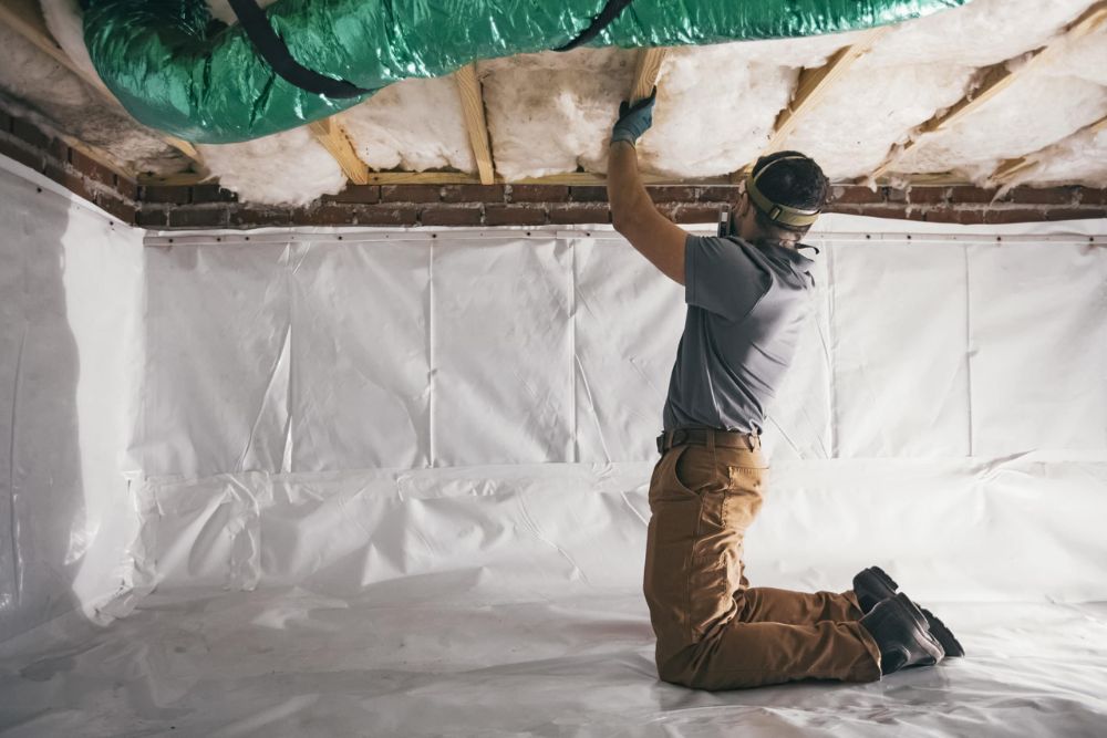 A man works on the ceiling in an unfinished basement, using tools and materials to complete the construction project.