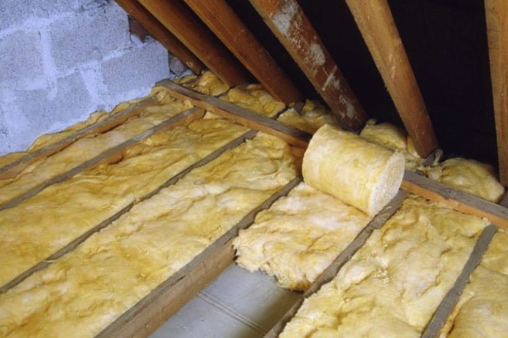 Insulation material covers wooden beams in an attic, providing thermal protection and energy efficiency.