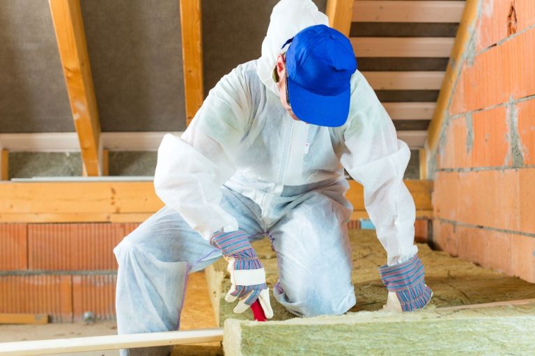 A man in a white suit and hat installs insulation, demonstrating his expertise in insulation services